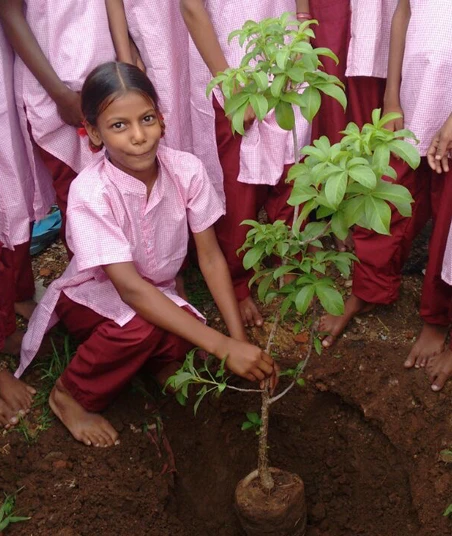 Girl planting sapling in a rural school in India