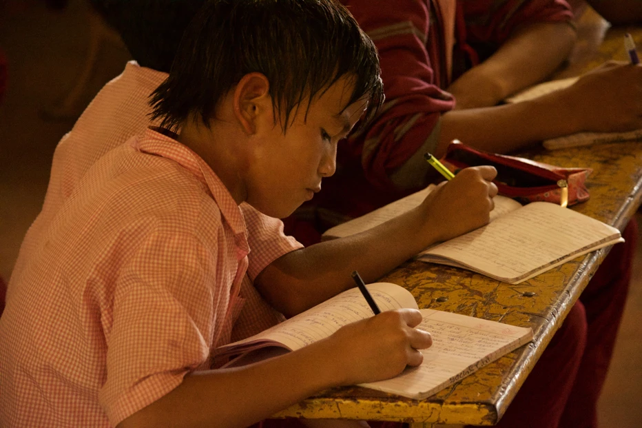 Boy writing on a desk in Care For Children school