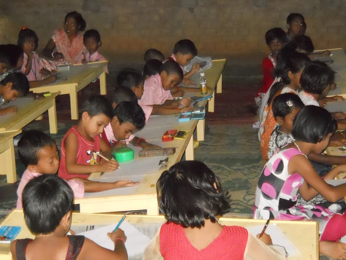 Children writing on new desks distributed by Care For Children