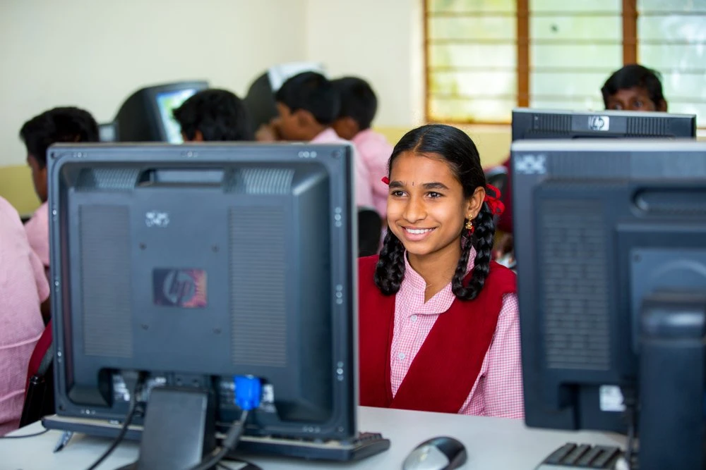 Smiling girl working on a computer in rural school